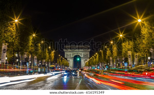 View of Arc de Triomphe and the avenue\
Champs-Elysees illuminated by night. Famous touristic places and\
romantic travel destinations in Europe. Urban landscape with night\
traffic. Long exposure.\
Toned
