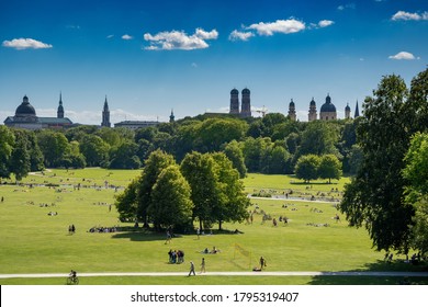 view from the arch of the English garden in Munich. Aerial view of the Munich cityscape with the "Englischer Garten" and the "Eisbach" river in front.  People sunbathing in English Garden in Bavaria