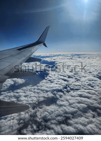 View from the areoplane window of the wing over clouds.