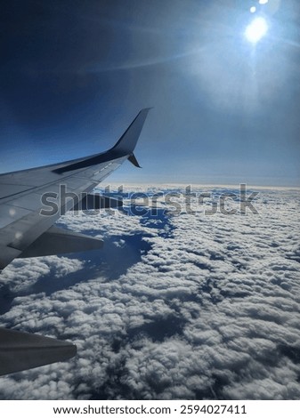 View from the areoplane window of the wing over clouds.