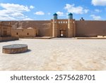 View of the Ark palace in Khiva, Uzbekistan, featuring historic walls, tiled domes, and a central courtyard under a bright blue sky