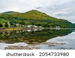 View of Arrochar village and Loch Long with reflections in water, Argyll and Bute, Scotland