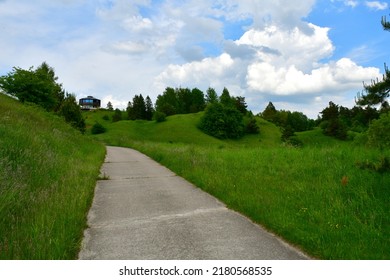 A View Of An Asphalt Road Leading Uphill Towards The Top Of A Hill Or Mountain, With Trees, Herbs, Shrubs And Other Flora Seen On Both Sides On A Cloudy Yet Warm Day In Poland Spotted During A Hike