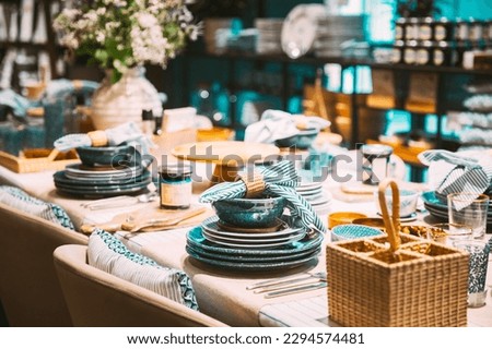View of assortment of decor for interior shop in store of shopping center. Home accessories and household products for dining room in store of shopping centre. View of dinnerware, plate, bowl on table