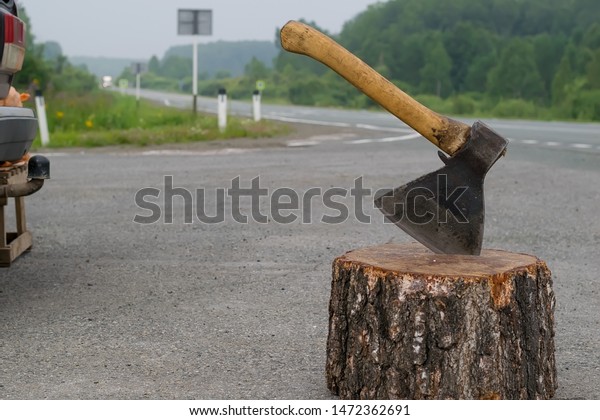 view of the ax, which is stick in a wooden\
chock on the background of a country\
road