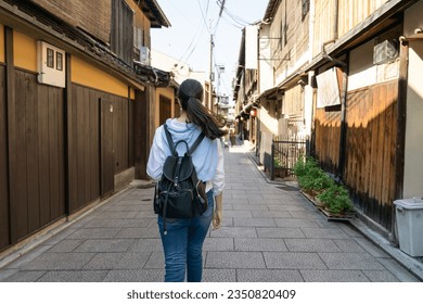 view from back asian Japanese woman visitor walking down alley lined with traditional wooden geisha houses on Gion Hanamikoji Street in Kyoto japan - Powered by Shutterstock