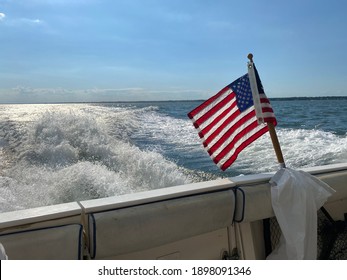 View From Back Of Boat Of American Flag And Boat Wake In Ocean