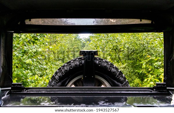 view of the back of a car with no windows and a black\
wheel on a rainy day