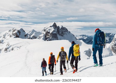 View from the back, five mountaineers descending down the snowy mountain, walking in a row 