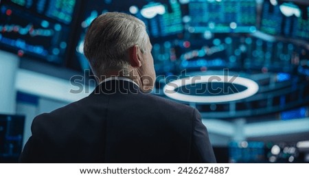View from the Back of a Middle Aged Man Working on the Floor in a Modern Stock Exchange Firm. Specialist Monitoring Companies and Funds, Securities, Derivatives, Investments on Multiple Screens