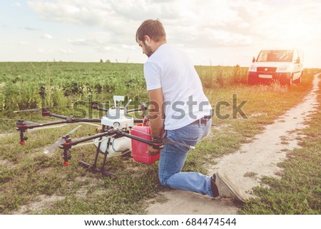 View from the back process of preparing agro drones for irrigation. A man agronomist pours liquid into a Octocopter .