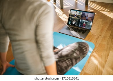 View From Back Of A Woman Having Virtual Yoga Class With Group Of People At Home On A Video Conference. Fitness Trainer Taking Online Yoga Classes Over A Video Call In Laptop.