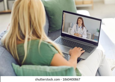 View From The Back Of A Woman Talking On A Video Call With Her Family Doctor Sitting On The Couch At Home. Concept Of Telemedicine And Patient Counseling Online.