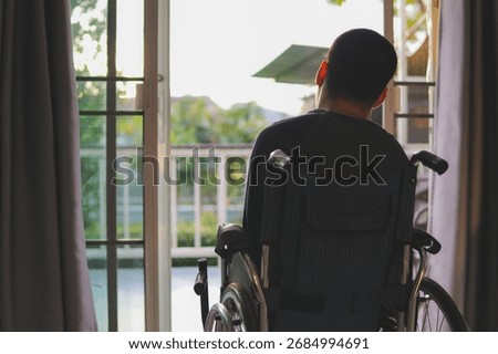 View from the back of a young man with disability in wheelchair looking out of his door with feeling sad, lonely and isolated,waiting for something or someone to come back,Concept caring for patients.