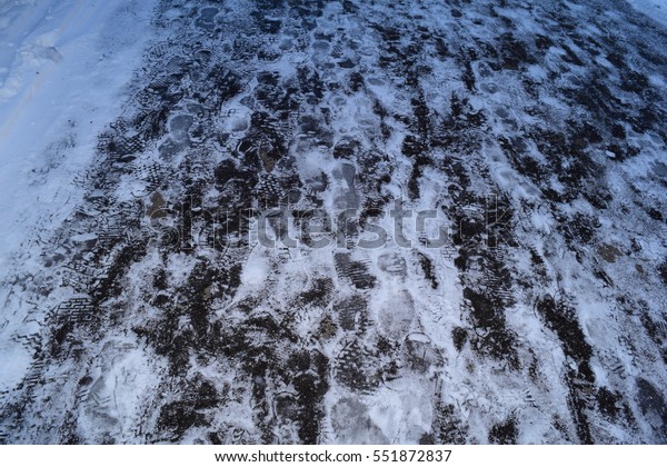 the view of the background of ice with footprints\
on the road in winter
