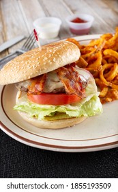 A View Of A Bacon Cheeseburger, With A Side Of Curly French Fries.