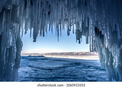 view of the Baikal ice from an ice cave with the stalactites of Olkhon Island hanging from above and on the sides during the day