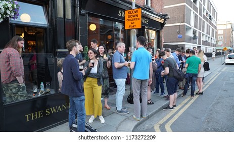 View Of The Bar District In Dublin Ireland. A Lot Of People Walking And Talking On The Pedestrian Road. Many Colorful Stores, Bars And Signs. Urban Picture Taken On 28th June 2018