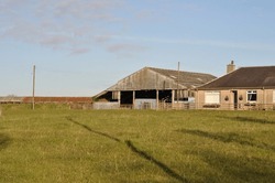 View Of Barn And Farm Buildings In Open Field On Sunny Day 