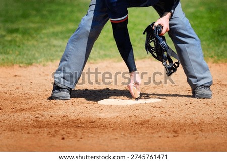View of Baseball Umpire Brushing Off and Cleaning Home Plate with Hand Brush for Ball Game