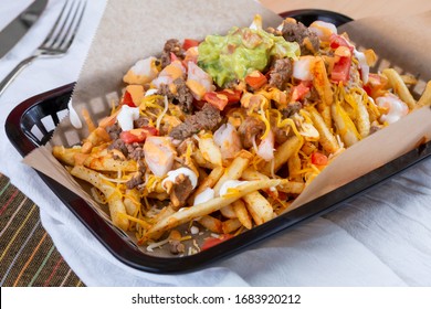 A view of a basket of carne asada fries, in a restaurant or kitchen setting.