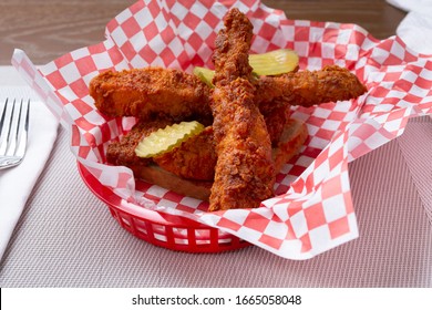 A View Of A Basket Of Spicy Breaded Chicken Strips Over A Slice Of White Bread Toast.