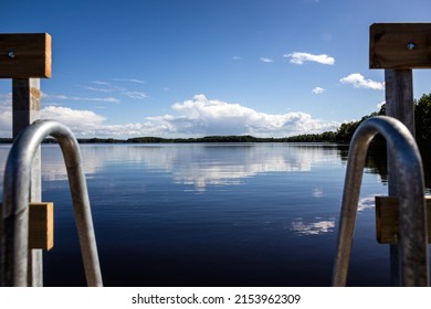 View from bathing ladder at a lake in Sweden with blue sky and some clouds
