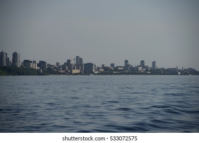 View of the beach and cityscape  with dense forest from the middle of the river