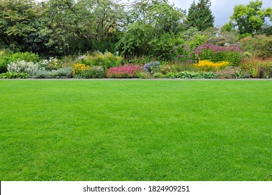 View of a Beautiful English Style Landscape Garden with a Lush Green Mowed Lawn and Colourful Flower Bed in Bloom - Powered by Shutterstock