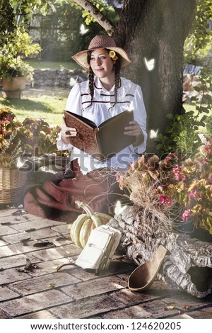 View of a beautiful girl in a classic dress reading a story book.