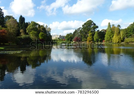 View with beautiful mirror reflection over still lake at Sheffield Park Garden in East Sussex, England, United Kingdom.