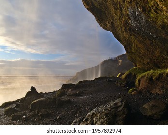 View of beautiful small cave behind famous waterfall Seljalandsfoss, a popular tourist destination located near ring road on the southern coast of Iceland, in the evening sun in winter.