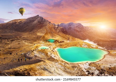 View at beautiful sunrise over Emerald lakes on Tongariro Crossing track, Tongariro National Park, New Zealand with a hot air balloon flying over the peaks