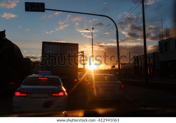 The view of the\
beautiful sunset on the road with cars in the city. A beautiful\
warm light. Traffic jam.
