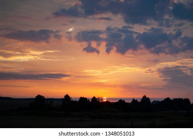 View of a Beautiful Sunset and Sky with dramatic clouds over a Silhouetted Land Horizont.