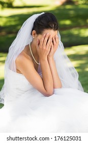 View of a beautiful worried bride sitting at the park