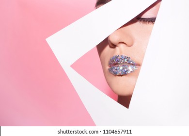 View of beautiful young woman with creative lips makeup through cutout in color paper