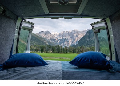 View from bed in camper van to green meadow in Zgornje Jezersko and Kamnik-Savinja Alps on a cloudy summer day in Slovenia