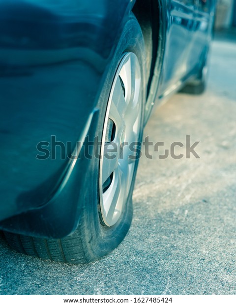 View from\
behind of flat rear tire on a car. Detail of car wheel break on\
driveway of parking lot. Burst tire background. Motor Vehicle\
Insurance and roadside assistance\
concept.
