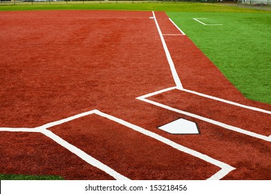 The view is from behind home plate looking towards first base with artificial turf at a school softball field. The bright colors of the artificial turf are a high contrast to a normal playing field.