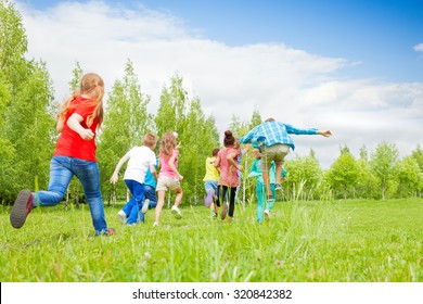 View From Behind Of Kids Running Through  Field