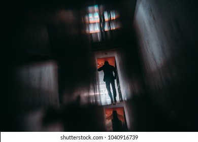 View From Behind Of Silhouette Of Man Entrepreneur Having Phone Talk While Moving Away Inside Of Dark Office Hall With Multiple Glass And Mirror Reflections, And Strong Chromatic Aberrations