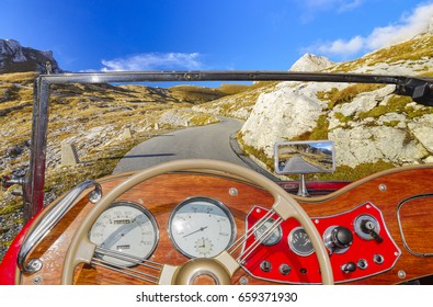 A View From Behind The Steering Wheel Of A Vintage Convertible Driving On A Mountain Road