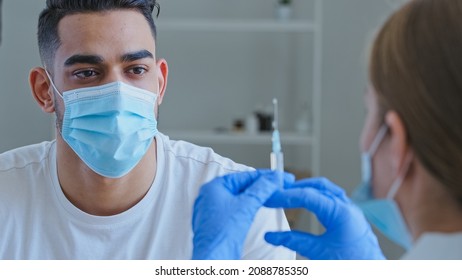 View From Behind Woman Doctor Nurse Holding Syringe With Drug Vaccine For Covid Male Patient Hispanic Arab Man In Mask Waves Hands No Refuses Disagrees With Vaccination Protests Against Treatment