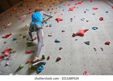 View from below of active guy during risky training on climbing wall
