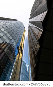 View from below of a cleaning worker on a scaffold or hanging gondola to clean the glass facade of a glass skyscraper in the City of London with his reflection in the facade.