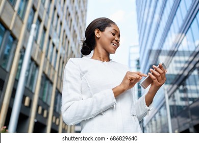 Blick von unten - süße afrikanisch-amerikanische Mädchen tippen Text auf Smartphone steht in der Mitte des großen Business Center in der Stadt am Sommertag