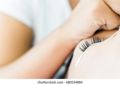 view from below of eyelash extension procedure, beautician hand working