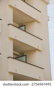 View from below of the facade of a building, close up on the geometrical features of the balconies. Modern residential concrete design.