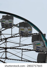 View from below a Ferris wheel in front  of a clear blue sky. 